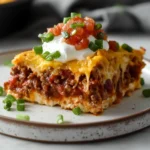 Close-up of the final Emily’s Excellent Taco Casserole, showcasing its melted cheese layers and crispy nacho top on a modern marble countertop
