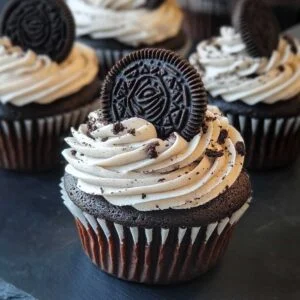 Close-up of Easy Oreo Cupcakes showing fluffy Oreo frosting and chocolate crumb, garnished with Oreo piece on ceramic plate.