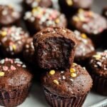 Mini Brownie Bites on a modern plate, showcasing crinkly tops and a fudgy chocolate center with colorful sprinkles on top.