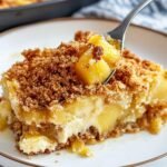 Close-up of Pineapple Dump Cake showing golden crumb topping and juicy pineapple chunks, served on a white plate with crispy texture.