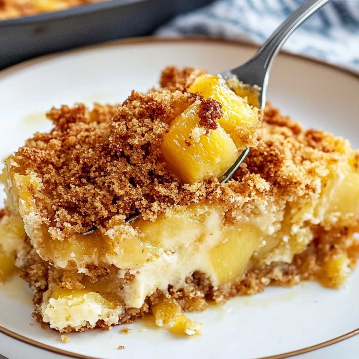 Close-up of Pineapple Dump Cake showing golden crumb topping and juicy pineapple chunks, served on a white plate with crispy texture.