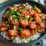 Sweet Chili Chicken on a modern marble countertop, showcasing its glossy glaze and topped with sesame seeds and fresh green onions.
