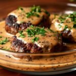 Amish Hamburger Steak Bake on a modern glass dish, showcasing its creamy mushroom gravy with browned beef patties and fresh parsley