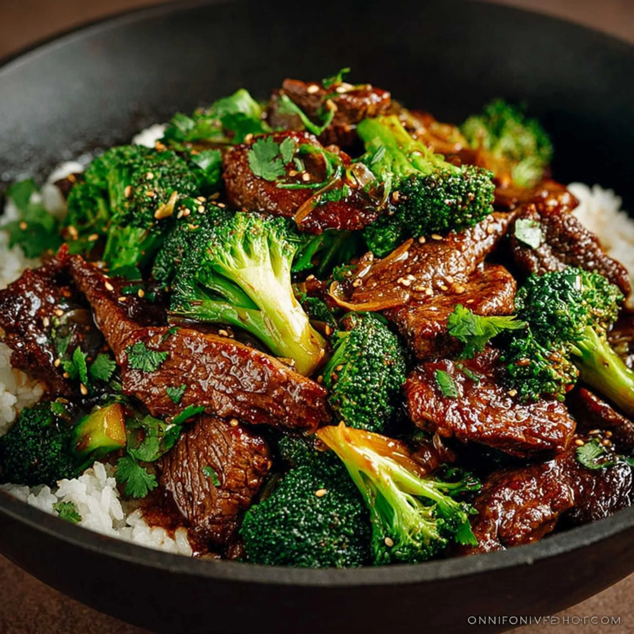 Chinese Beef and Broccoli in a dark bowl over rice, showcasing its glossy sauce coating the tender beef and vibrant green broccoli