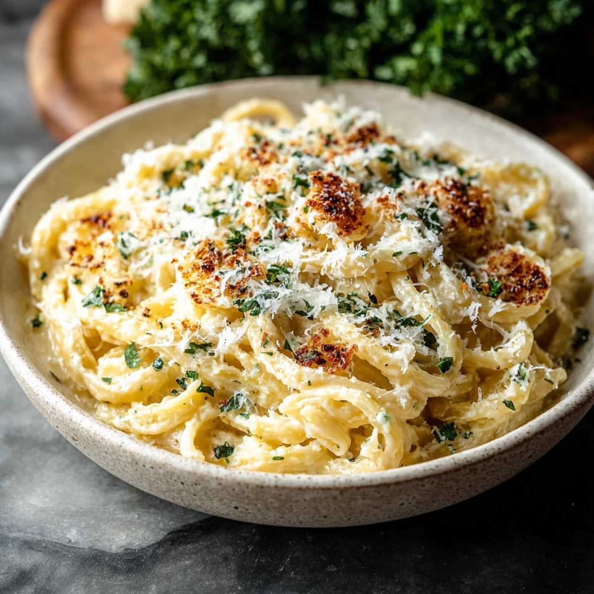 Creamy Garlic Pasta in a ceramic bowl, showcasing its silky cream sauce, toasted parmesan topping, and fresh parsley garnish