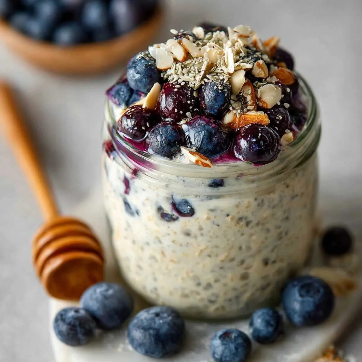 Healthy Blueberry Overnight Oats in a mason jar on a modern marble countertop, showcasing its creamy texture with juicy blueberries and sliced almonds.