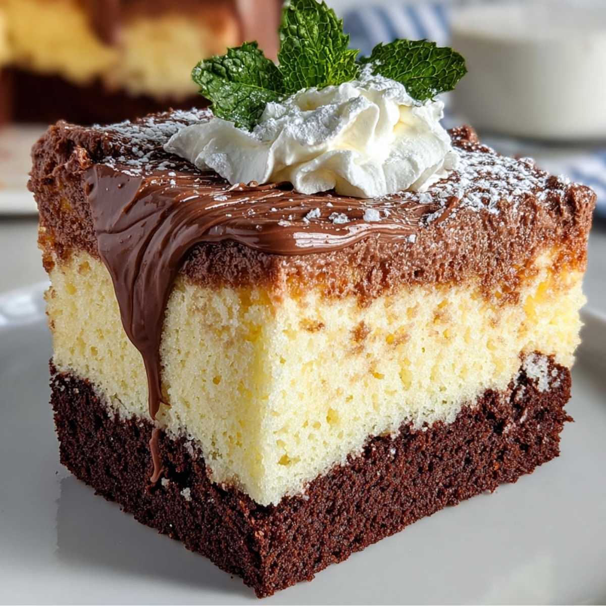 Close-up of a slice of Italian Love Cake, showing moist chocolate cake, creamy ricotta, and chocolate pudding layers, topped with whipped cream and mint.