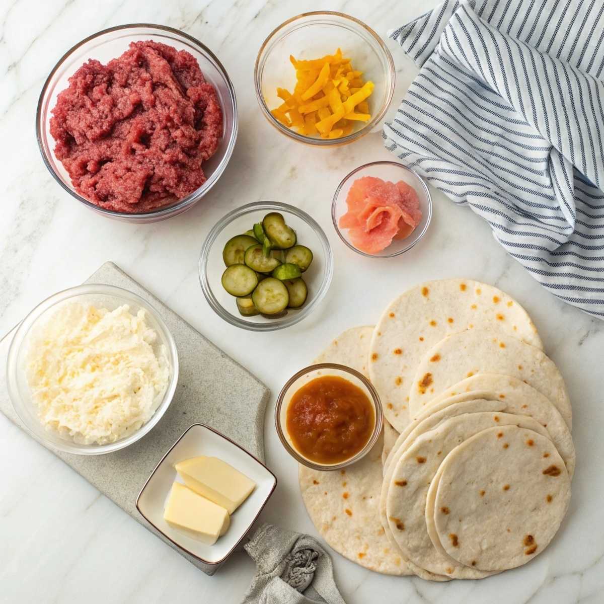Fresh ingredients for Smashburger Quesadillas including ground beef, American cheese, and flour tortillas arranged on a modern marble surface