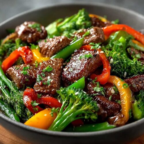 Close-up of Beef Stir Fry with Vegetables showing tender seared beef and crisp broccoli, garnished with sesame seeds in a dark bowl
