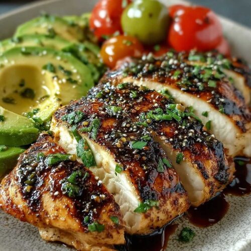 Close-up of sliced Grilled California Avocado Chicken showing moist white interior and glossy dark brown balsamic glaze, garnished with fresh parsley on a light grey plate