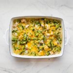 Chicken broccoli rice casserole in a white baking dish, showing melted cheddar cheese, tender chicken pieces, and broccoli florets.