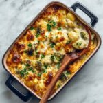 Close-up of paneer and broccoli bake showing creamy melted cheese, golden potatoes, roasted broccoli, and fresh herb garnish.