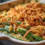 Close-up of Southern green bean casserole showing tender green beans in creamy sauce topped with crispy golden fried onions.