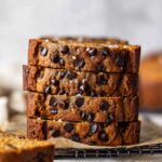 Close-up of Chocolate Chip Banana Bread slices stacked, showing moist banana crumb, melted chocolate chips, and golden brown edges.